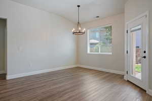 Unfurnished room with plenty of natural light, a chandelier, and wood finished floors