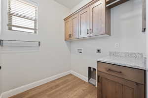 Laundry area featuring washer hookup, cabinet space, hookup for an electric dryer, and light wood-type flooring