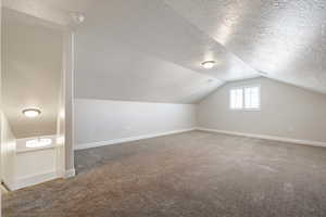 Bonus room featuring carpet flooring, a textured ceiling, and lofted ceiling