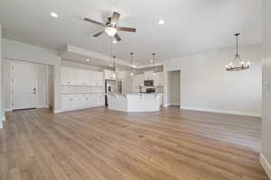 Unfurnished living room with a ceiling fan, recessed lighting, a chandelier, and light wood-style floors