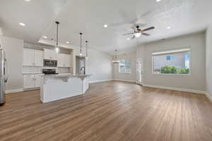 Kitchen with a ceiling fan, a kitchen breakfast bar, recessed lighting, white cabinets, and light wood finished floors