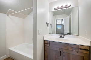 Full bathroom with vanity, lofted ceiling, shower / bath combination, and a textured ceiling