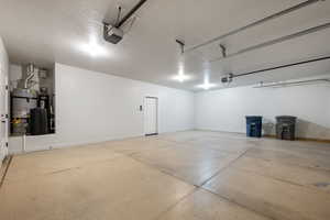 Garage featuring secured water heater and a garage door opener