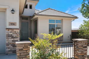 Entrance to property with stucco siding, a tiled roof, and stone siding