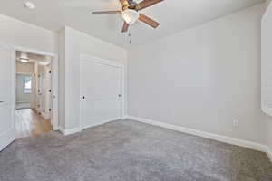 Unfurnished bedroom featuring carpet floors, a closet, and a ceiling fan