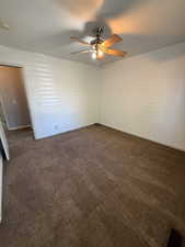 Spare room featuring ceiling fan and dark carpet