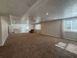 Below grade area with carpet floors, a textured ceiling, and recessed lighting