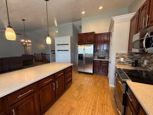 Kitchen with stainless steel appliances, decorative backsplash, light countertops, a textured ceiling, and recessed lighting