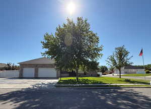 View of front facade featuring driveway, brick siding, and a garage
