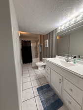 Bathroom featuring vanity, shower / bath combination with curtain, and a textured ceiling