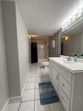Full bathroom with vanity, shower / bath combo with shower curtain, and a textured ceiling