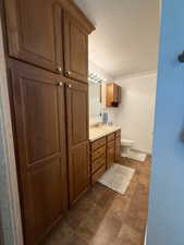 Bathroom with double vanity, a textured ceiling, and crown molding