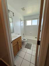Bathroom featuring vanity, shower / tub combination, tile patterned floors, and a textured ceiling
