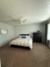 Carpeted bedroom with a textured ceiling and ceiling fan