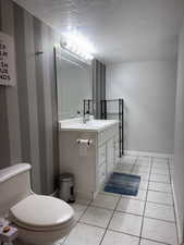 Half bath featuring a textured ceiling, vanity, and tile patterned floors