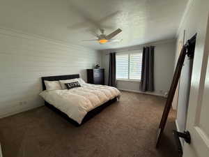 Carpeted bedroom featuring ornamental molding, a textured ceiling, and ceiling fan