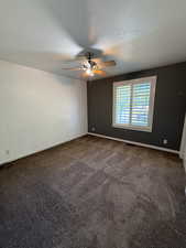Spare room featuring a ceiling fan, dark carpet, and a textured ceiling