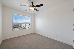 Carpeted spare room with ceiling fan and baseboards