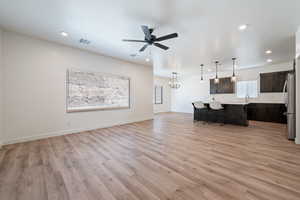 Living area with light wood finished floors, a ceiling fan, recessed lighting, and a chandelier