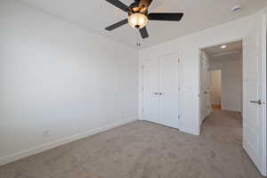 Unfurnished bedroom with carpet, a closet, and a ceiling fan