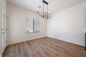 Spare room featuring a chandelier and light wood-type flooring