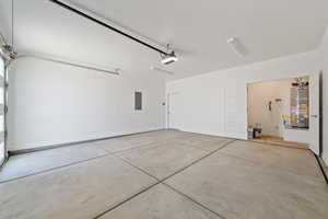 Garage with water heater, electric panel, and a garage door opener