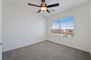 Carpeted empty room featuring baseboards and a ceiling fan