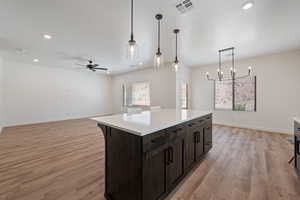 Kitchen featuring a chandelier, light wood-type flooring, ceiling fan, light countertops, and hanging light fixtures