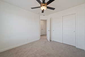Unfurnished bedroom with carpet, a closet, and a ceiling fan