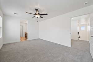 Unfurnished room with light colored carpet and a ceiling fan