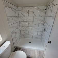 Full bath featuring a tile shower and wood finished floors