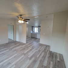 Unfurnished living room with light wood-style floors, a textured ceiling, and ceiling fan