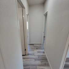 Corridor with a textured wall and wood finished floors