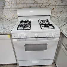 Kitchen view of white appliances, light stone counters, and decorative backsplash