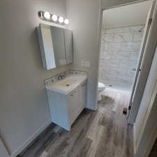 Full bath with vanity, a stall shower, and wood finished floors