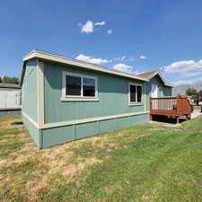 Rear view of house featuring a deck with mountain view and a yard