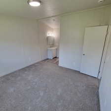 Unfurnished bedroom with light colored carpet and connected bathroom