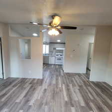 Unfurnished living room with light wood-style floors, a ceiling fan, and a textured ceiling