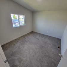 Empty room featuring carpet flooring, lofted ceiling, and a textured ceiling