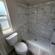 Bathroom featuring a tile shower and wood finished floors