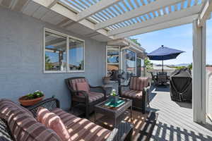 Wooden terrace with outdoor dining space, a grill, a pergola, and an outdoor hangout area