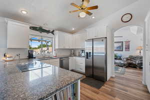 Kitchen featuring stainless steel appliances, ceiling fan, white cabinets, backsplash, and recessed lighting