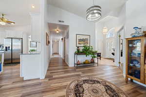 Foyer entrance featuring high vaulted ceiling, a chandelier, light wood finished floors, and ceiling fan