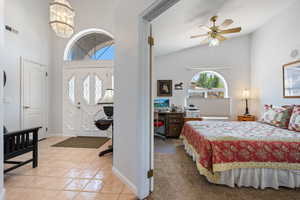 Foyer entrance featuring light tile patterned floors, a chandelier, ceiling fan, and high vaulted ceiling