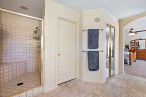 Ensuite bathroom featuring a shower stall, ceiling fan, and tile patterned flooring