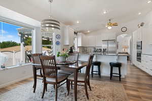 Dining area with a ceiling fan, light wood-style flooring, lofted ceiling, arched walkways, and recessed lighting