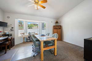 Dining space featuring a desk, carpet, a textured ceiling, a ceiling fan, and vaulted ceiling