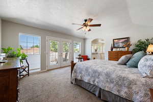 Carpeted bedroom featuring french doors, access to exterior, a textured ceiling, and arched walkways
