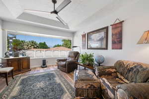 Living area featuring a textured ceiling, plenty of natural light, wood finished floors, and ceiling fan