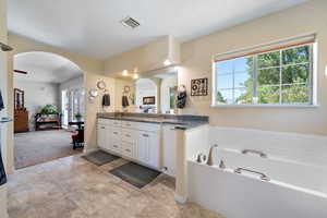 Full bathroom with double vanity, a garden tub, healthy amount of natural light, and tile patterned flooring